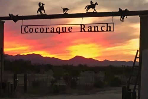 Cocoraque Ranch entrance sign at sunset with cowboy silhouettes in Marana, Arizona