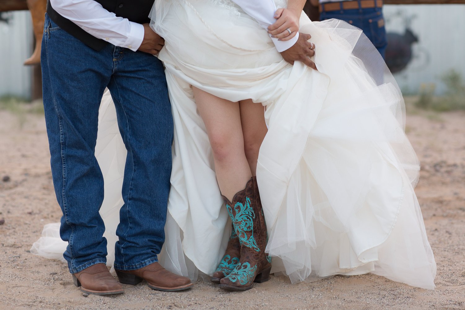 Bride wearing turquoise cowboy boots lifting her wedding dress beside the groom at Cocoraque Ranch, a rustic wedding venue in Tucson, Arizona.