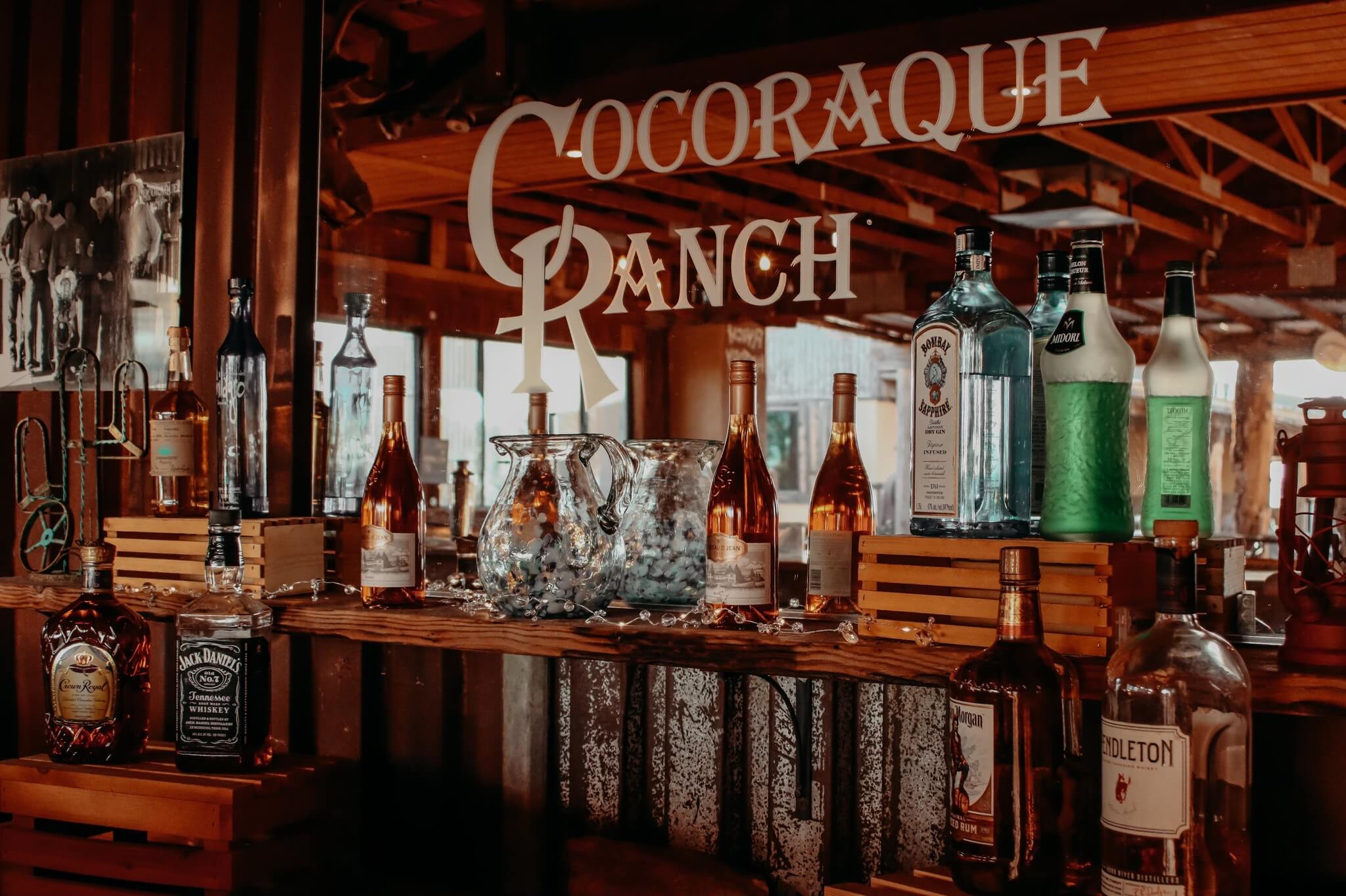 Rustic bar with liquor bottles and glass pitchers at Cocoraque Ranch, a Tucson wedding venue offering authentic Arizona ranch weddings.